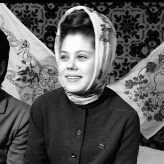 Two young women posing before patterned textiles.