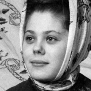 Woman in headscarf holding a teddy bear.