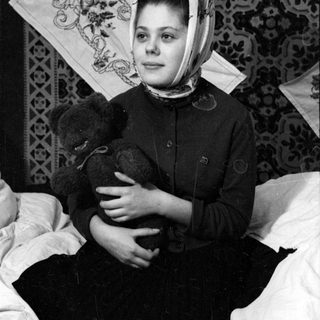 Woman in headscarf holding a teddy bear.