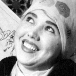 Person in headscarf against patterned textile background.