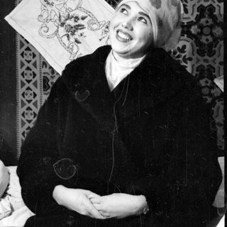 Person in headscarf against patterned textile background.