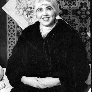 Person in headscarf against patterned textile background.
