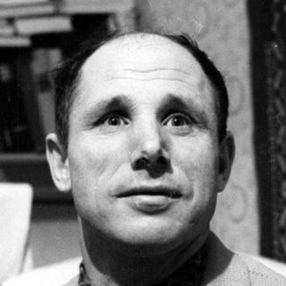 Portrait of a man in a blazer and checkered shirt.