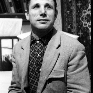 Portrait of a man in a blazer and checkered shirt.