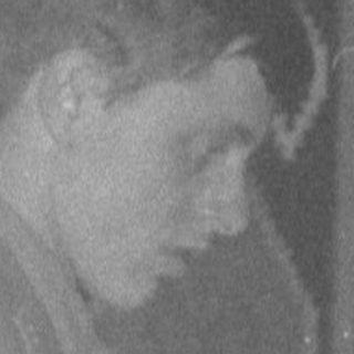 Man in military uniform holding fabric in a room.