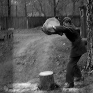 Person in suit lifting heavy object in woods.