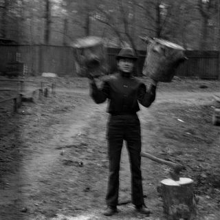 Man holding two wooden buckets in a forest.