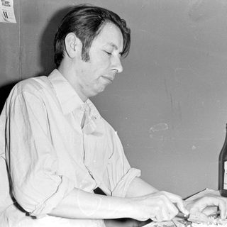 Man eating at a table with a bottle.