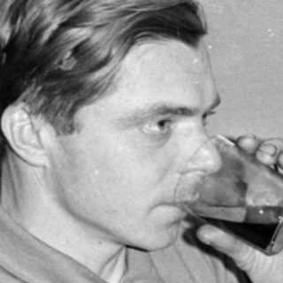 Man drinking from a glass next to a crutch.