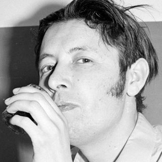 Man with sideburns drinking from a glass.