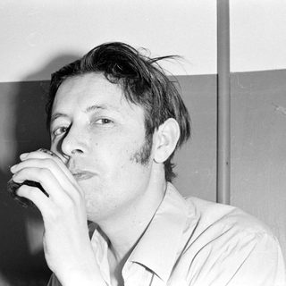 Man with sideburns drinking from a glass.
