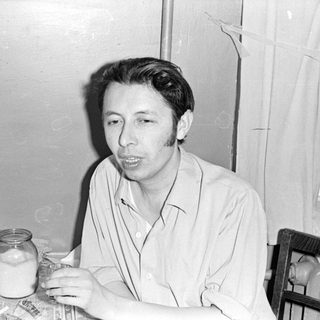 Man sitting at a table with a jar.