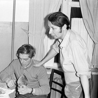 Two men indoors at a table with food.