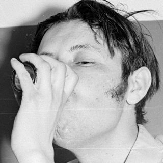 Man drinking from a small bottle.