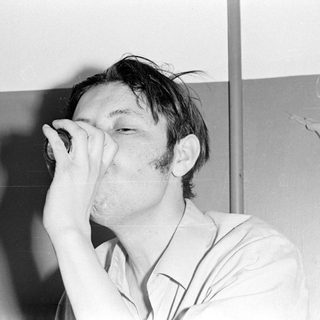 Man drinking from a small bottle.