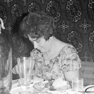 Woman at a table with a seltzer bottle.