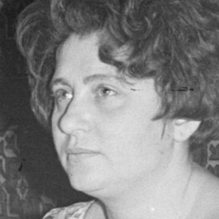 Woman sitting at a table with a seltzer bottle.