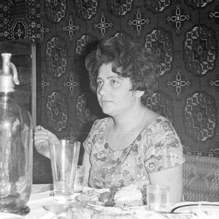 Woman sitting at a table with a seltzer bottle.