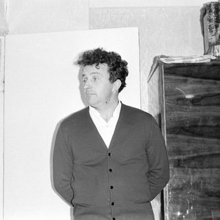 Man in a cardigan standing in a room.