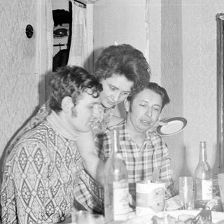 Three people at a table with a mirror reflection.